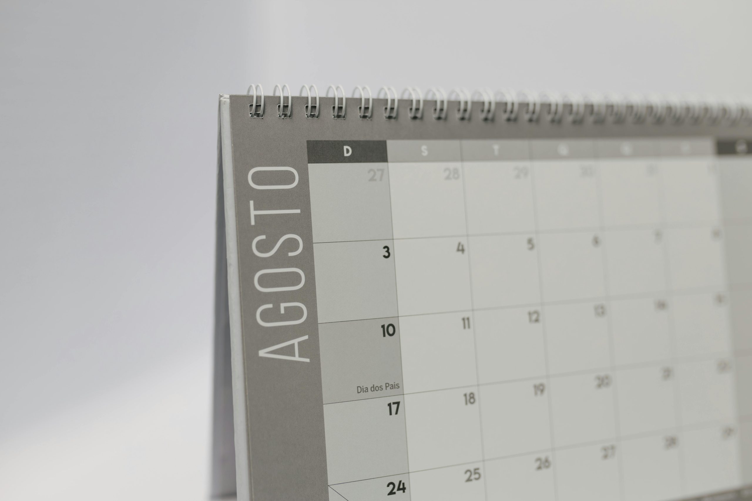 Close-up of a desk calendar showing August in Portuguese with a minimalist layout.