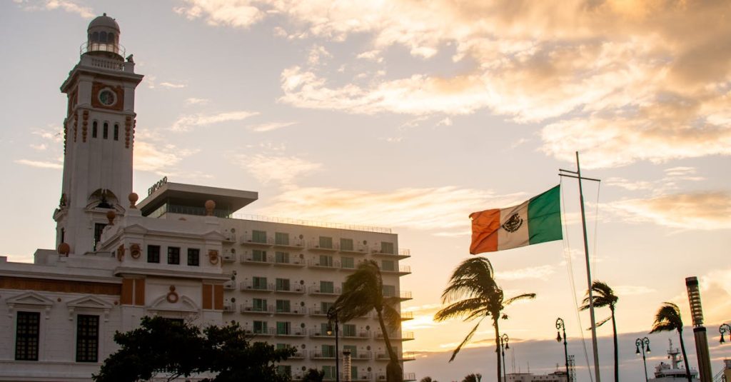 Beautiful Mexican flag waving near a historic clock tower at sunset in Veracruz.